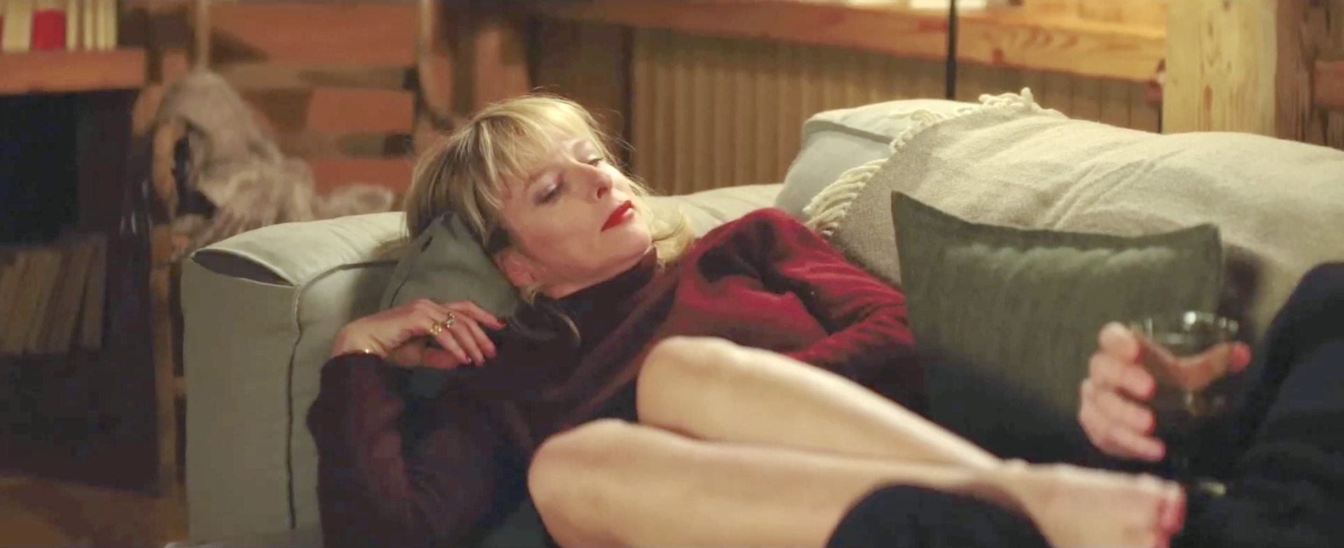 Karin Viard pose altièrement ses pieds nus sur l'entrejambe d'un homme docile en lui intimant l'ordre de masser ses pieds dans une fascinante scène de fétichisme du pied du film L’Amour est un crime parfait