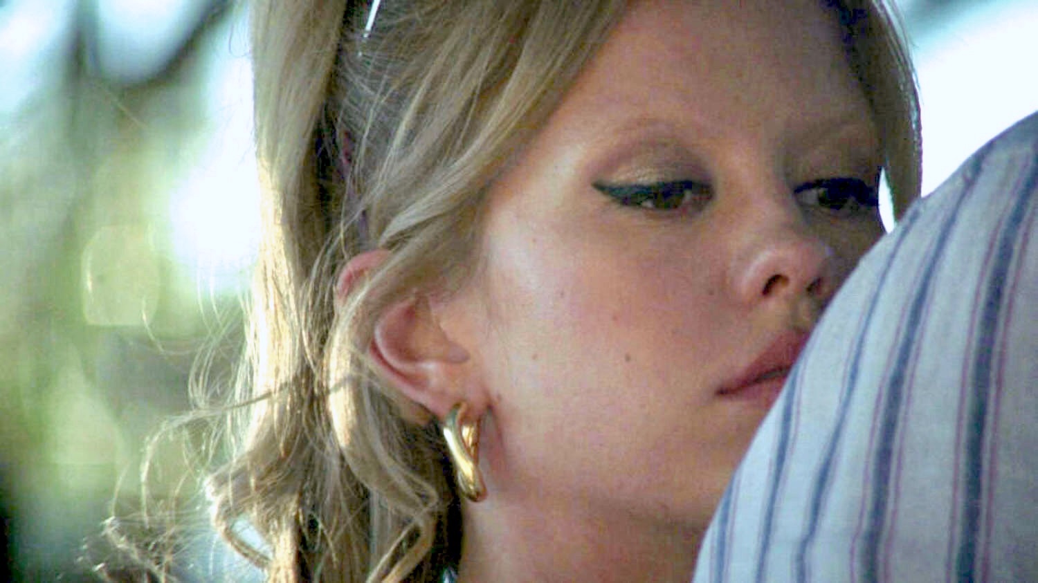 Mia Goth masturbe à main nue le pénis d'un homme en se tenant debout derrière lui et la jeune femme altière continue sa masturbation de la verge jusqu'à l'éjaculation par terre dans le film Infinity Pool en 2023
