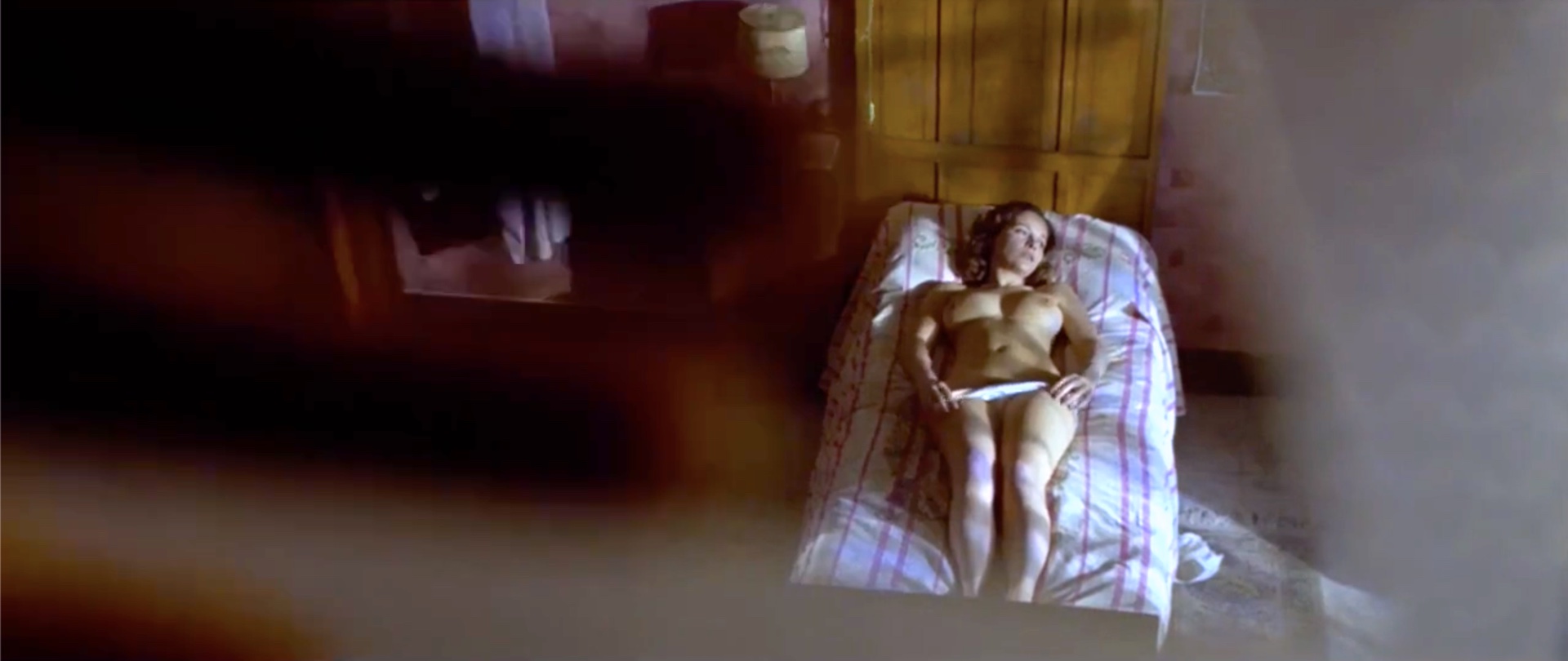 Laura Antonelli nue interprète Angela une jeune domestique glissant sa main dans sa culotte pour se masturber en sachant qu'elle est observée par des voyeurs dans le film Malicia en 1973