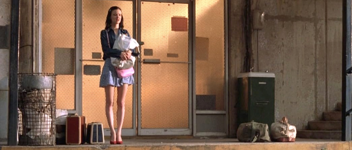 Adele Corners incarnée par Juliette Lewis à 18 ans attend le couple qui va la prendre en voiture pour un périple choquant jusqu'en Californie dans le film Kalifornia en 1993