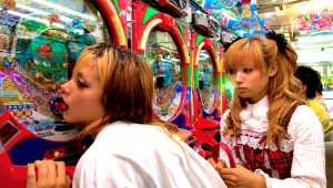 Anna Tsuchiya se frotte lascivement contre un pachinko en désirant de l'argent à l'intérieur d'une salle de jeux japonaise sous le regard de sa copine Kyoko Fukada dans le film Kamikaze Girls en 2004